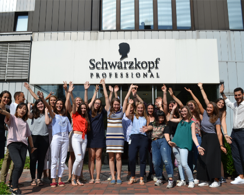 Raznoliki Henkelov tim stoji navija ispred profesionalne zgrade Schwarzkopf i podiže ruke