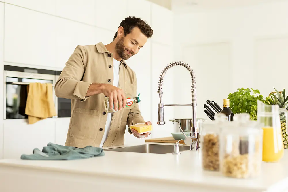 Muškarac u kuhinji pere suđe